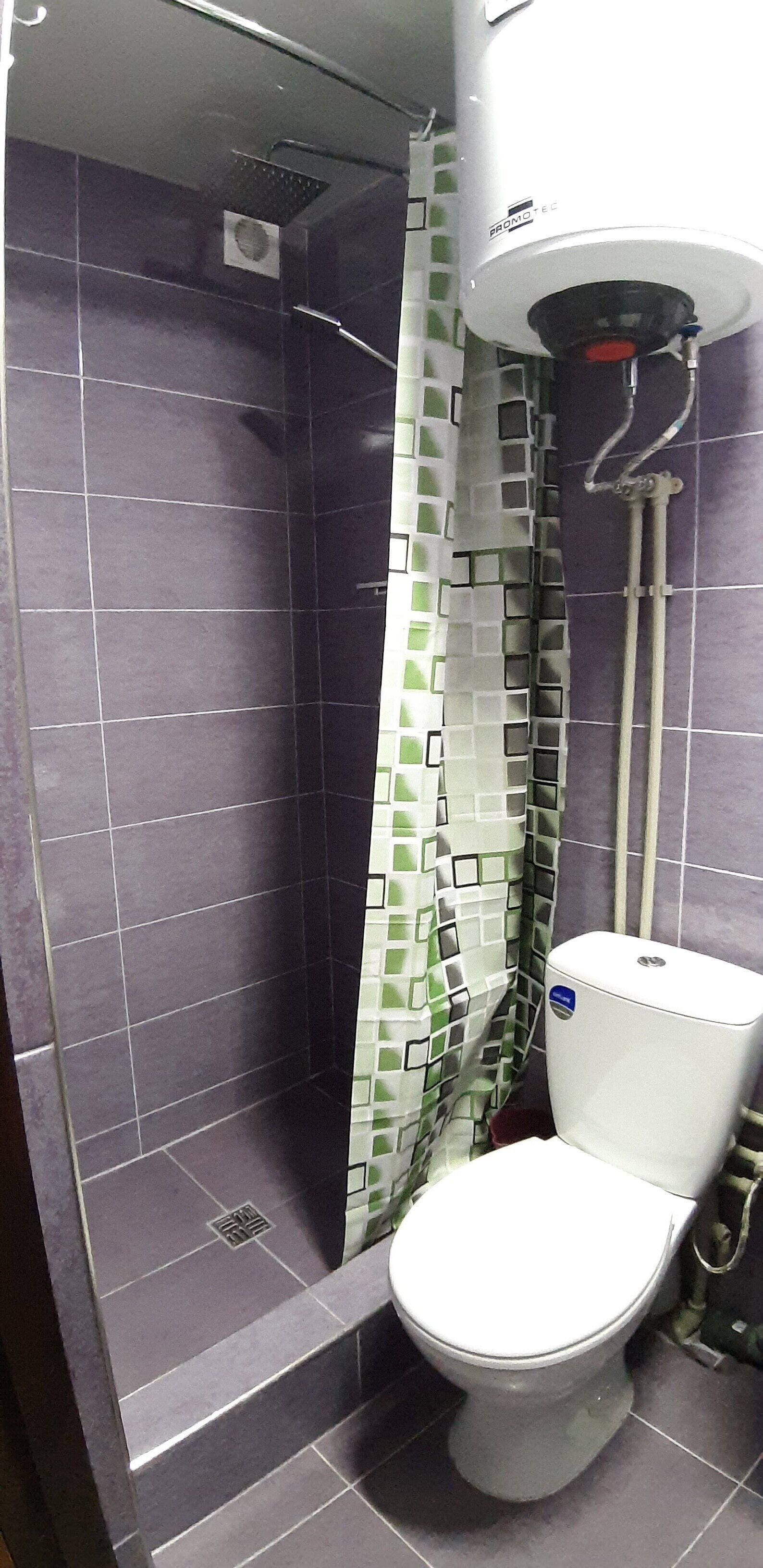 Un baño con ducha, inodoro y pared de azulejos.