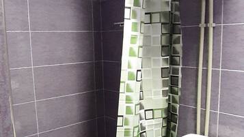 Un baño con ducha, inodoro y pared de azulejos.