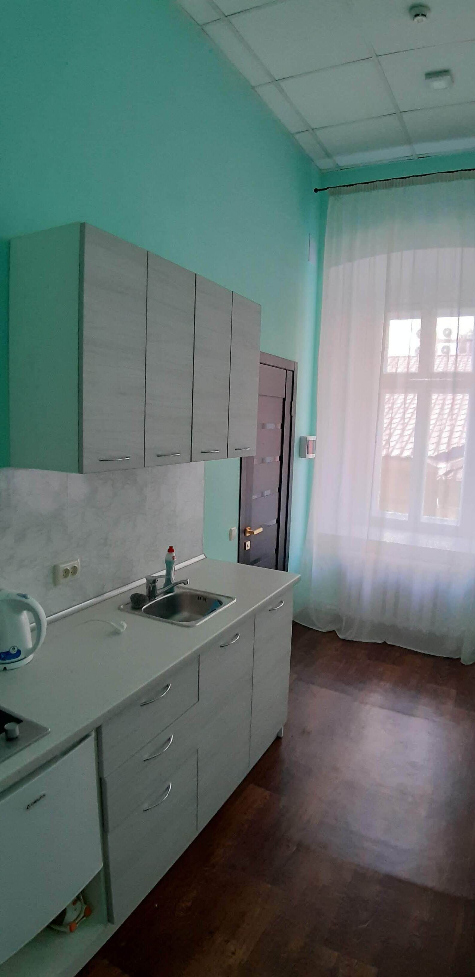 A kitchen with a sink, cabinets, and a window with curtains.