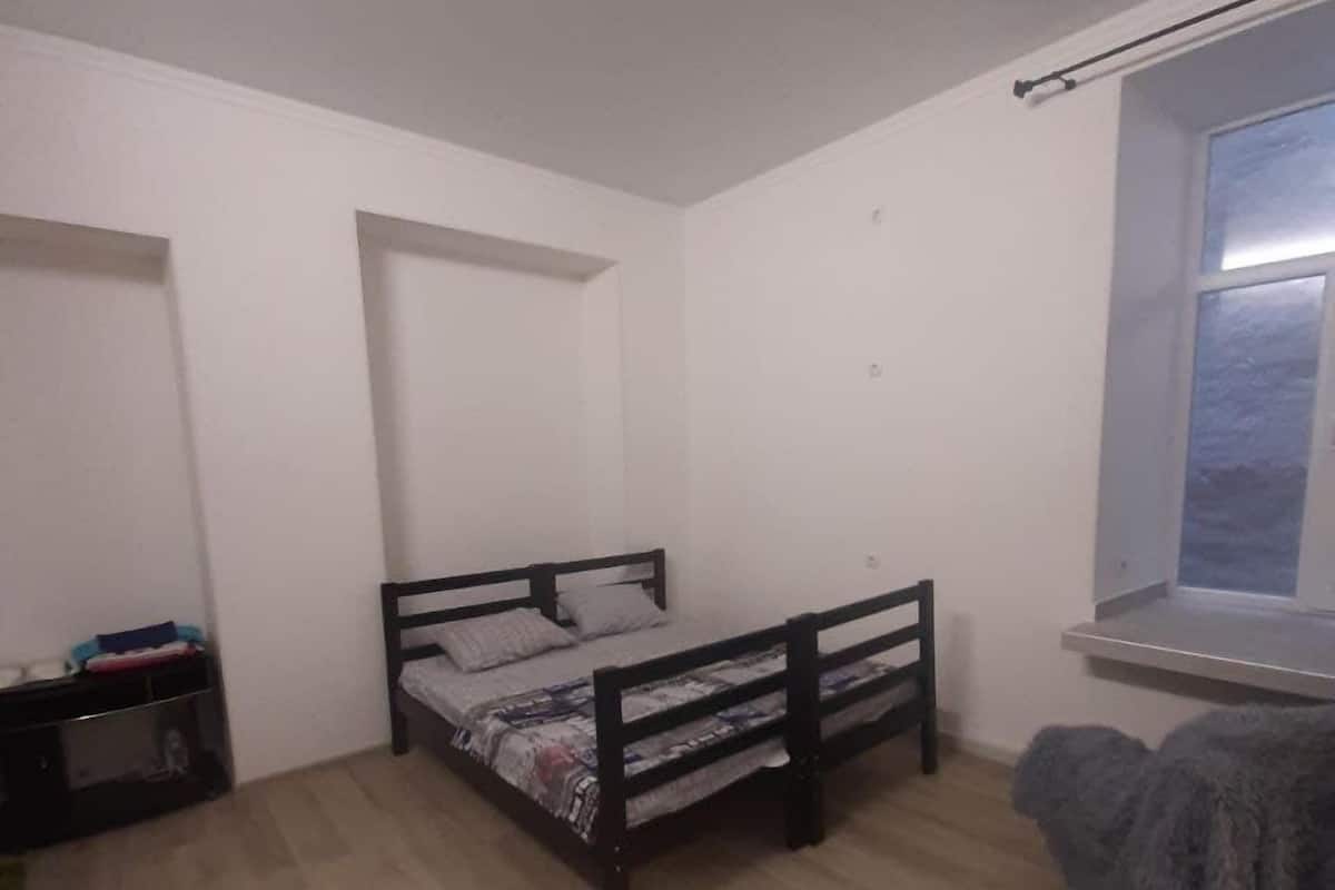 Un dormitorio con una cama individual, una ventana, un escritorio pequeño y una silla.