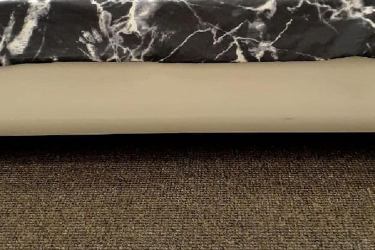 A bed with a black and white marble-patterned bedspread, two pillows, and a wooden headboard.