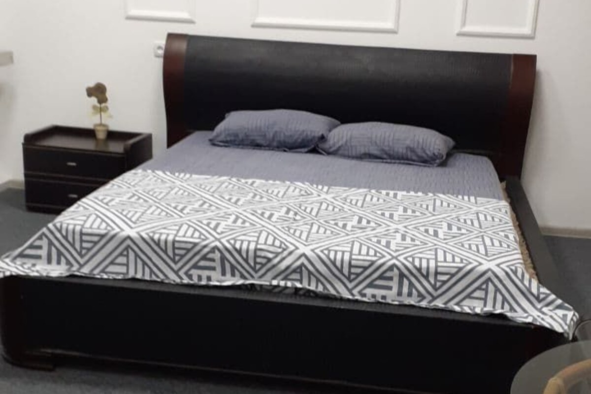 A bedroom with a bed, a nightstand, a small table, and a chair.
