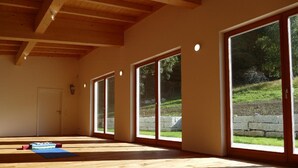 A spacious room with large sliding glass doors, wooden flooring, and a sloped ceiling. - Kraftquelle Waldhäuser (Neuschoenau)