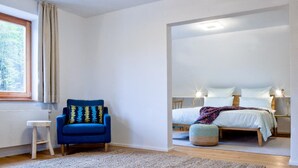 A bedroom with a bed, bedside tables, a chair, and a window. - Kraftquelle Waldhäuser (Neuschoenau)