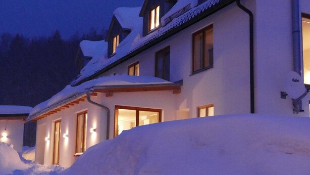 A snow-covered building with multiple windows and a satellite dish. - Kraftquelle Waldhäuser (Neuschoenau)