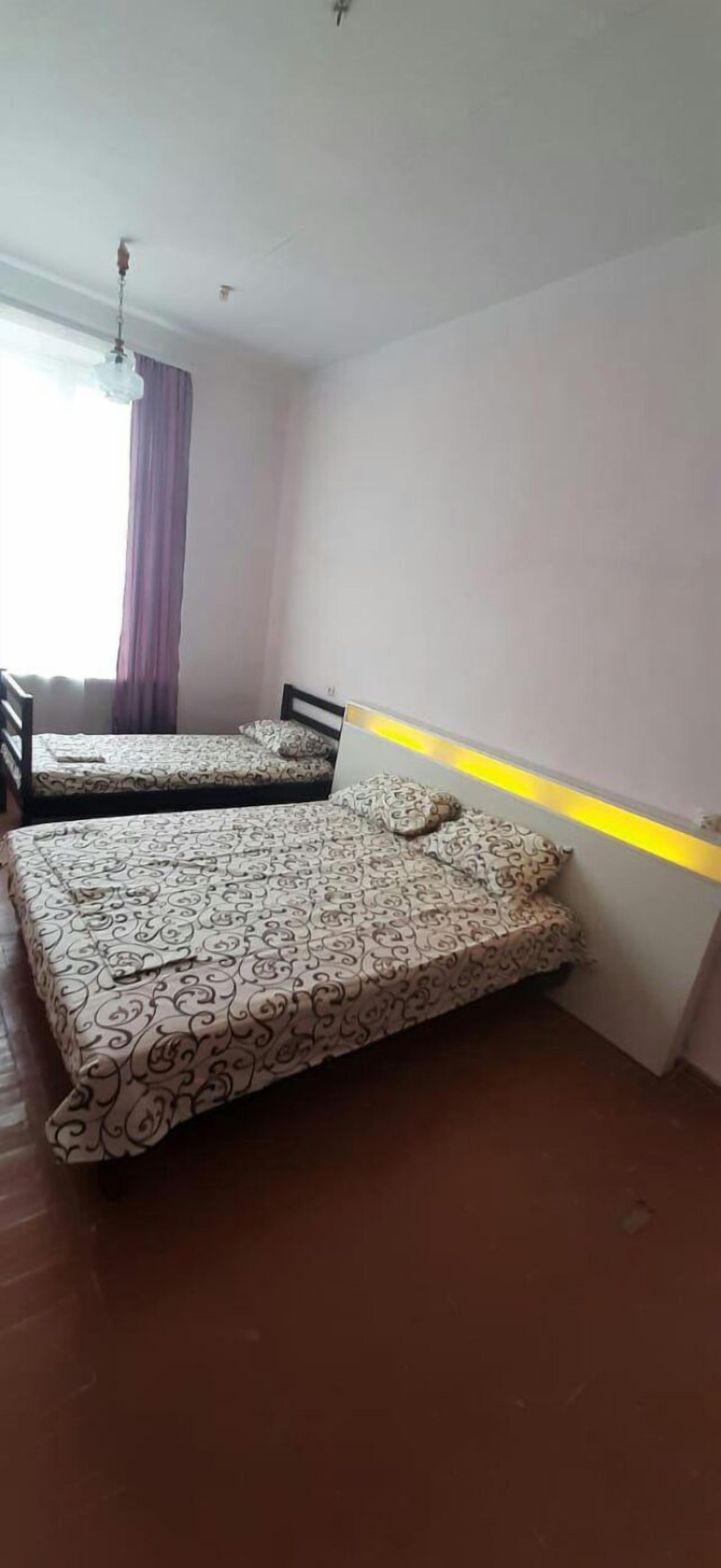 Una habitación con dos camas, una ventana con cortinas y un ventilador de techo.