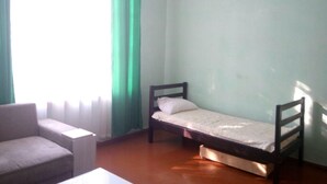 A small room with a single bed, a chair, and a table.