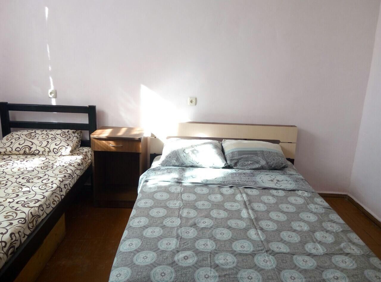 Une petite pièce simple, avec deux lits simples, une table de chevet et une prise électrique au mur.