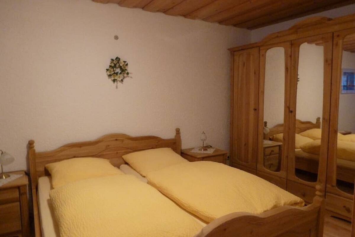 Une chambre à coucher avec un lit en bois, une table de chevet et une armoire.