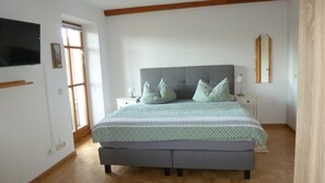 A bedroom with a bed, nightstands, a TV, and a window. - Appartementhaus Osserblick (Lohberg)