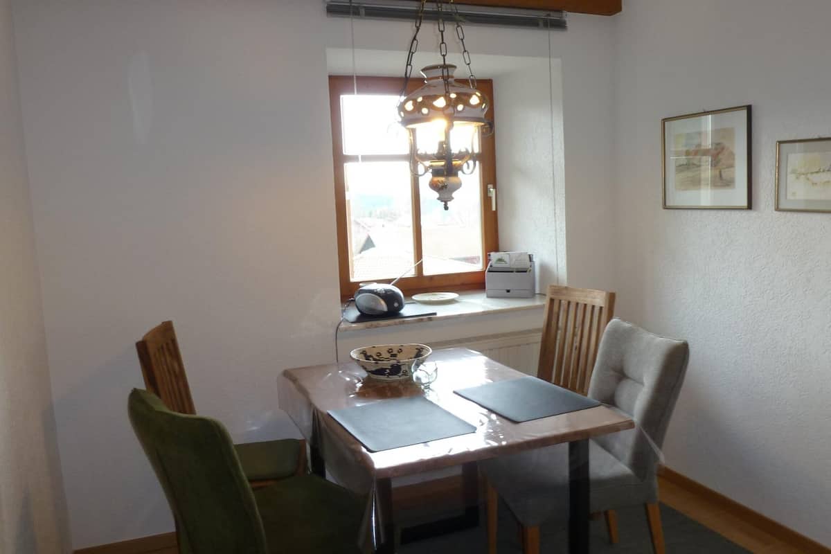 Un espace repas comprenant une table et des chaises, une fenêtre avec vue et un luminaire au plafond.