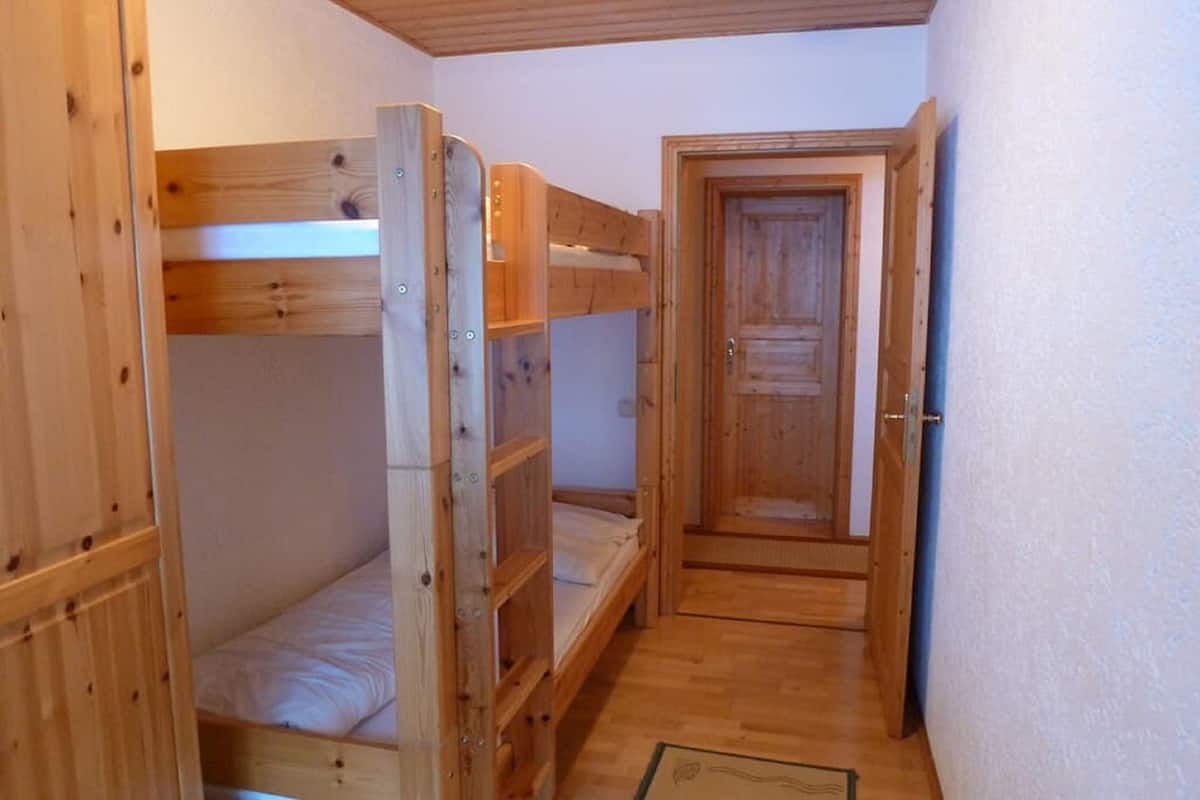 Une petite pièce étroite avec deux lits superposés et une porte.