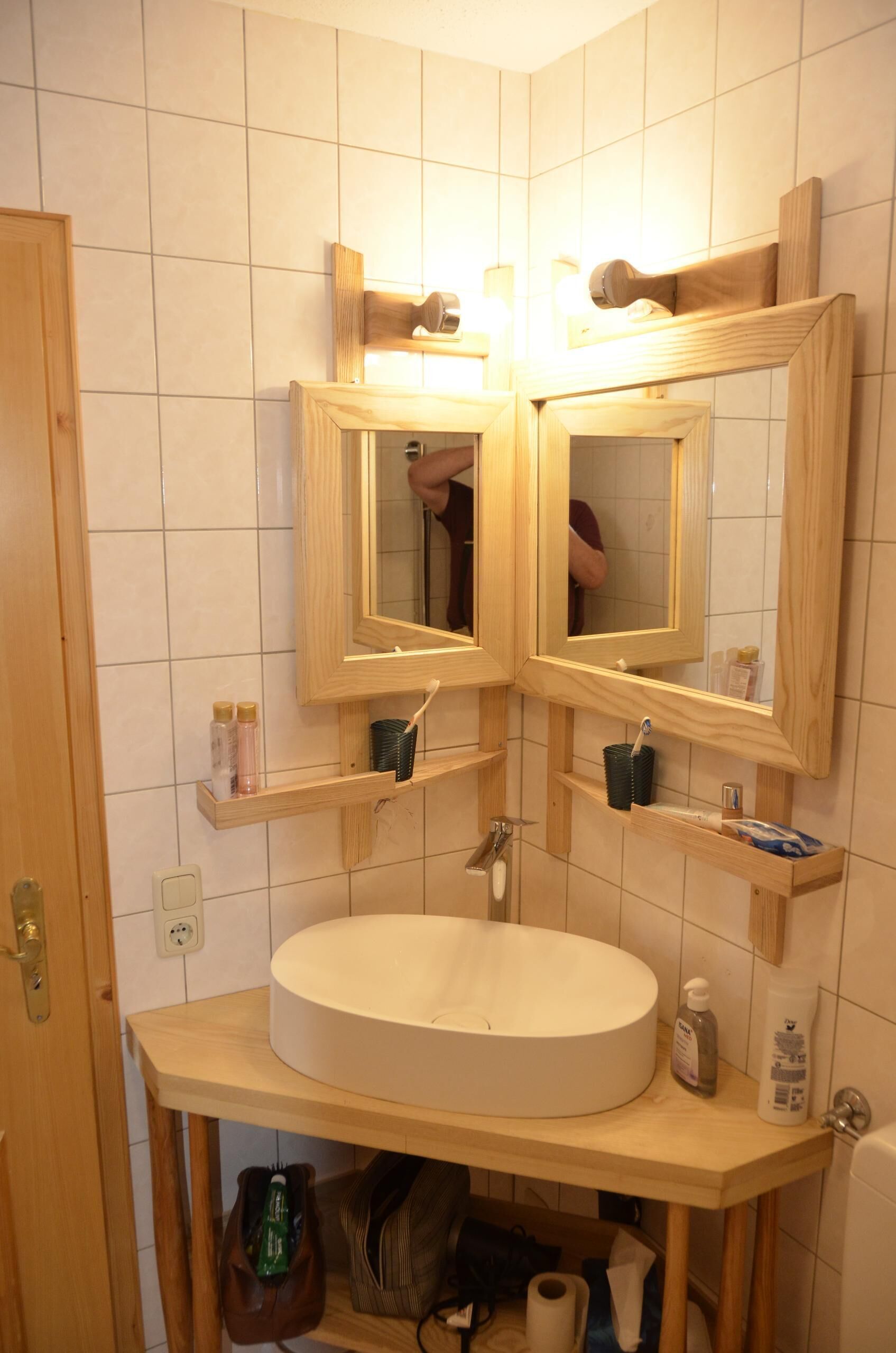 Une salle de bain avec un lavabo rond, des étagères en bois, un miroir et un porte-serviettes.