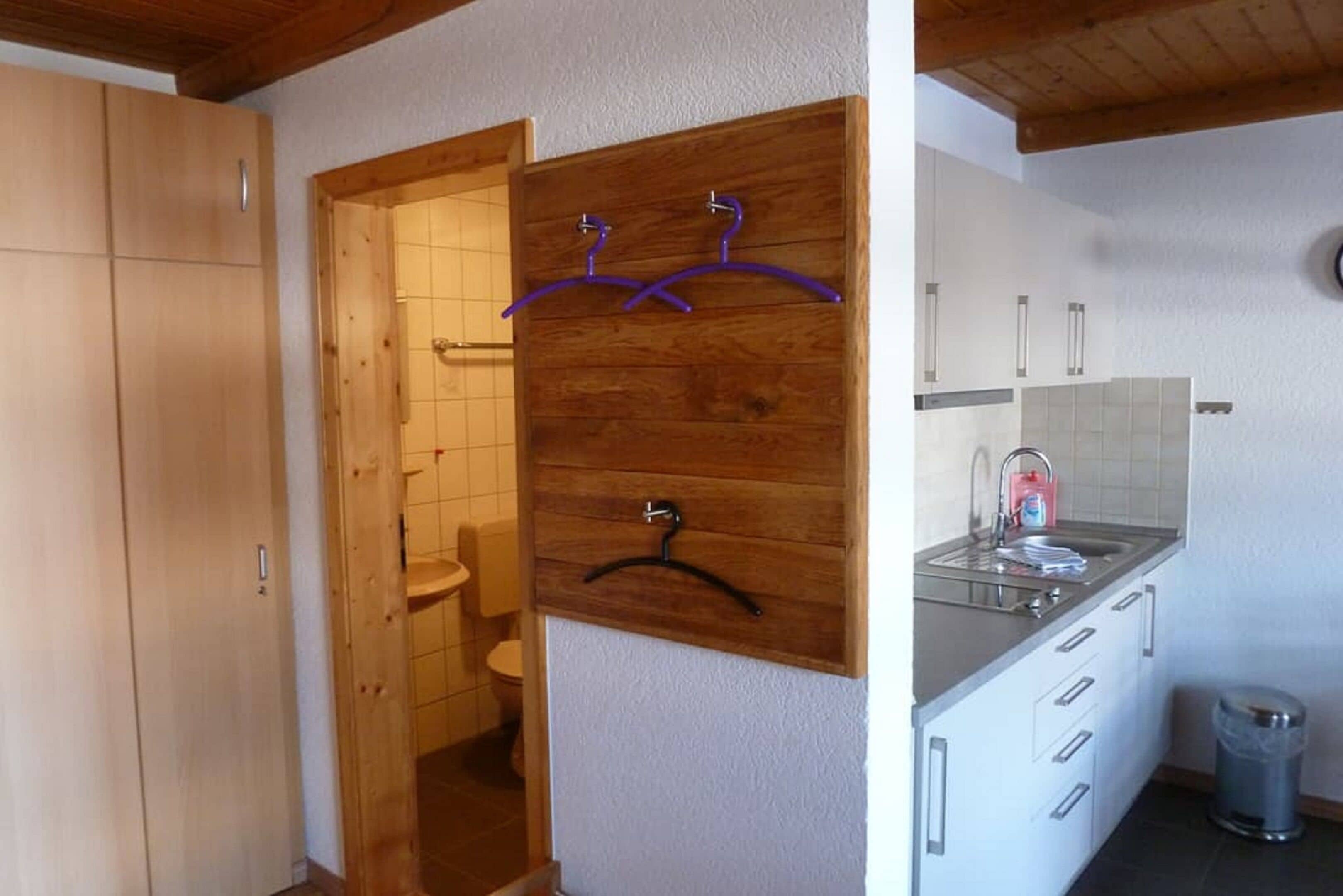 A bathroom with wooden cabinets, a sink, and a hanging rack.