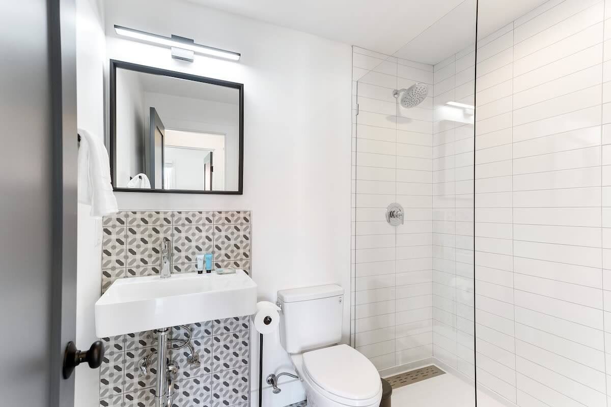 A modern bathroom with a white sink, toilet, and shower.