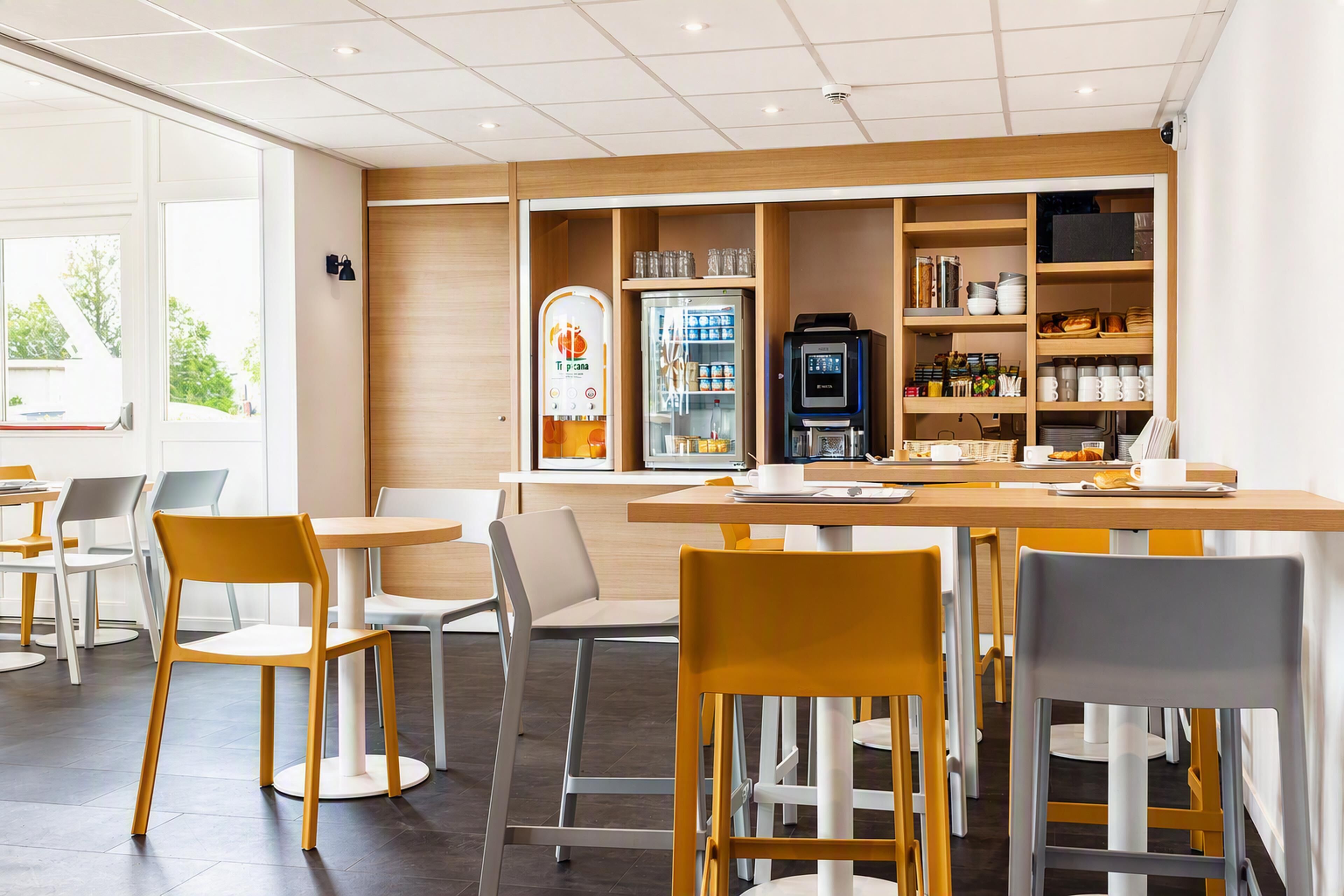 A modern cafe with a wooden counter, seating area, and a self-service coffee machine.