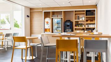 A modern cafe with a wooden counter, seating area, and a self-service coffee machine.