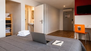 A bedroom with a bed, a laptop, a notebook, a chair, a wardrobe, a bathroom, and a TV. - PREMIERE CLASSE BEAUNE (Montagny-les-Beaune)