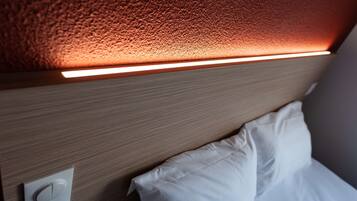 Un primo piano di una testiera in legno con una striscia luminosa integrata e una presa di corrente.
