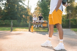 Uma pessoa em um caminho pavimentado em um parque, com árvores ao fundo.