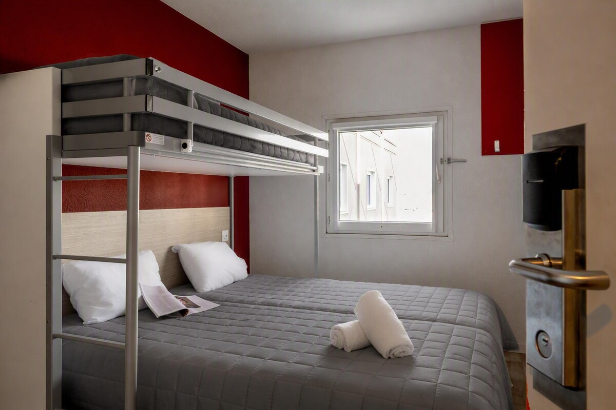 A bunk bed room with a window, a door, and a TV.