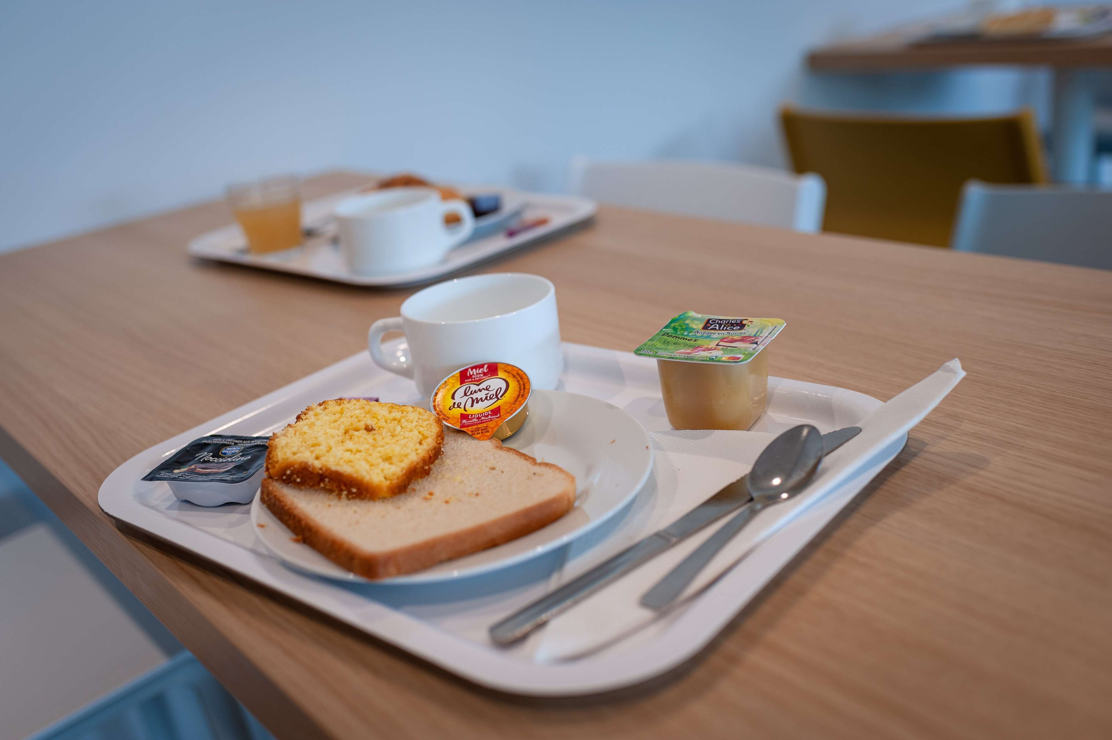 Un plateau de petit-déjeuner avec des toasts, de la confiture, une tasse et un petit pot de yaourt.