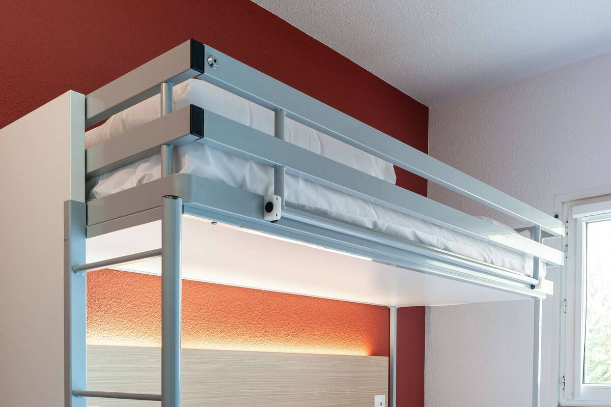 A bunk bed with a ladder, white bedding, and a wooden headboard.