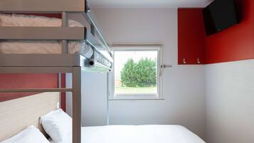 Een slaapkamer met stapelbed, een raam, een aan de muur bevestigde televisie en een rode kast.