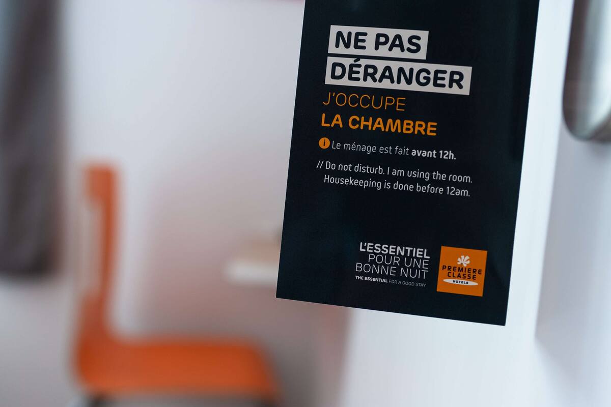 A sign with text in French, indicating housekeeping is done before 12am.