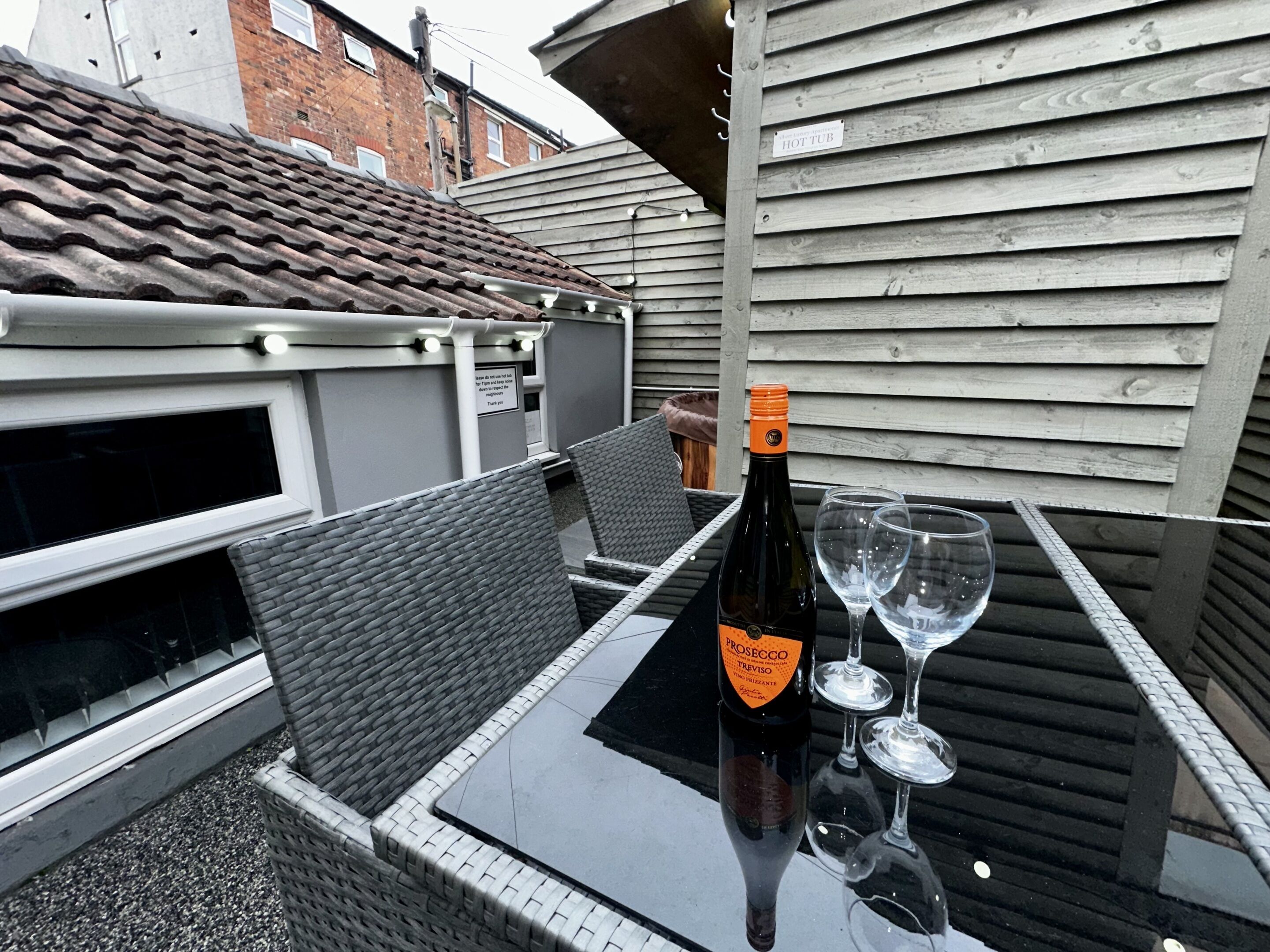 Una botella de vino Prosecco Treviso sobre una mesa con dos copas de vino vacías.
