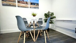 A modern dining area with a table and two chairs, a potted plant, and a radiator on the wall. - Albert Luxury Hottub and Jacuzzi Apartments (Blackpool)