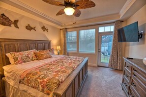A bedroom with a bed, a ceiling fan, a TV, and a sliding glass door leading to a patio. - Coastal Club * 5BR Luxury Beach House (LEWES)