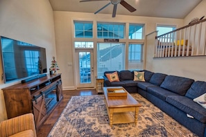 A living room with a large TV, a sofa, a coffee table, and a patterned rug.