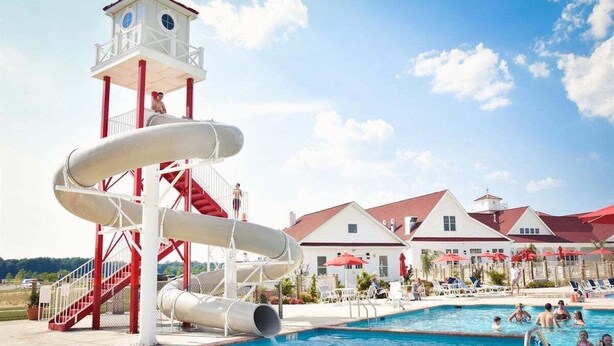 Un parque acuático con un tobogán de múltiples carriles, una piscina y una torre de salvavidas.