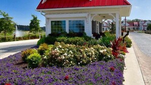 Un edificio blanco con tejado rojo y una torre, rodeado de un jardín con diversas flores.
