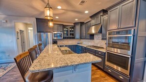 Una cocina con encimeras de granito, electrodomésticos de acero inoxidable y muebles de color oscuro.