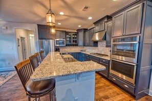 A kitchen with granite countertops, stainless steel appliances, and dark cabinetry.
