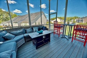 A covered outdoor deck with a sofa, chairs, and a table.