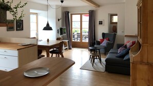 A spacious living area with a wooden dining table, a sofa, and a cabinet. - Ferienwohnung Oma Rosa mit Traumblick und Zentrumsnähe (Berchtesgaden)