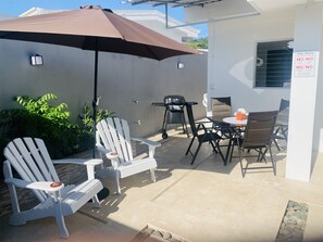 Relax on the patio with a round table and comfortable seating for four, shaded by an umbrella.