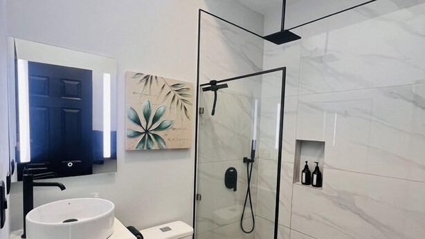 Un bagno moderno con lavandino bianco, toilette e cabina doccia in vetro.