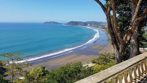 Vista sulla costa con spiaggia, alberi e cielo sereno.