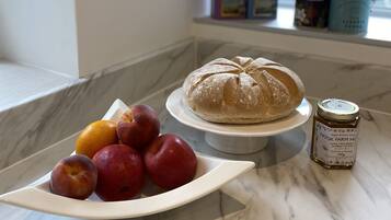 A kitchen counter with a loaf of bread, a plate of fruit, and a honey jar.