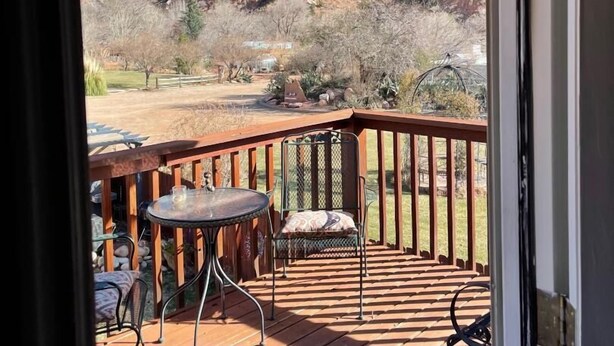 A wooden deck with a table and chairs, overlooking a mountainous landscape. - Harvest House Inn (Springdale)