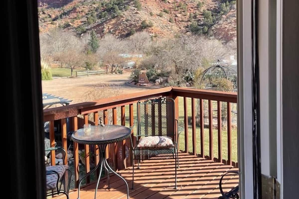 A wooden deck with a table and chairs, overlooking a mountainous landscape.