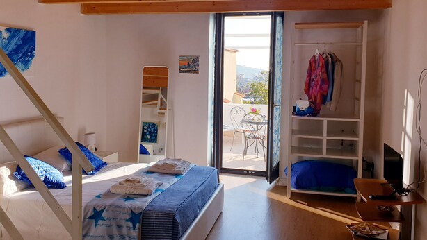 Une chambre avec un lit, une armoire, un bureau et un balcon.