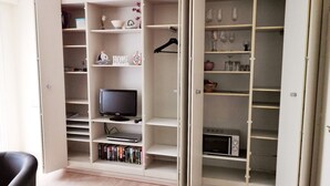 Ein Zimmer mit integriertem Fernseher, Bücherregalen, einer Mikrowelle und einem Weinregal.