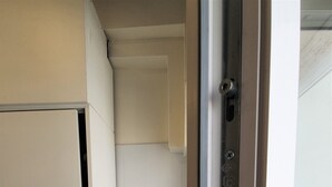 Um corredor estreito com uma porta branca à esquerda e um sanitário à direita.