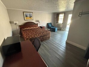 A hotel room with a bed, a desk, a chair, and a window. - OYO Economy Inn (Pleasantville)