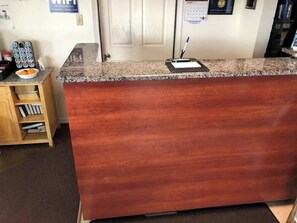 A reception desk with a wooden finish, a calendar, and a pen on the counter. - OYO Economy Inn (Pleasantville)